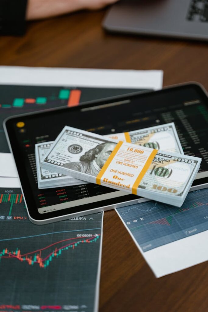 Mastering the First Impression: Your intriguing post title goes here Stack of $100 bills placed on a tablet with financial graphs, symbolizing digital finance.